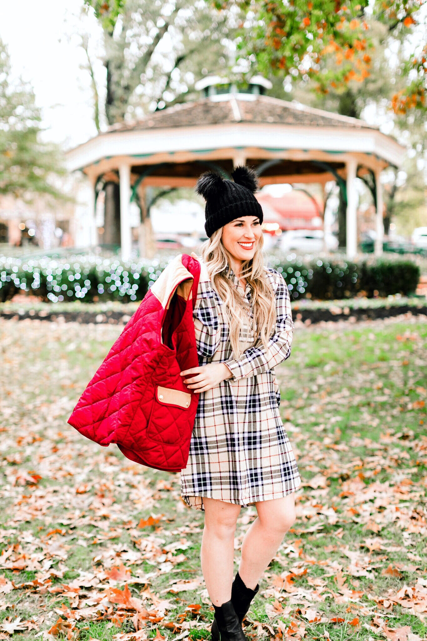 Cute Vests to layer in the Winter, featured by top US fashion blog, Walking in Memphis in High Heels: image of a woman wearing a Lauren James plaid dress, a Lauren James red vest, Sole Society black booties and an ASOS double pom pom beanie