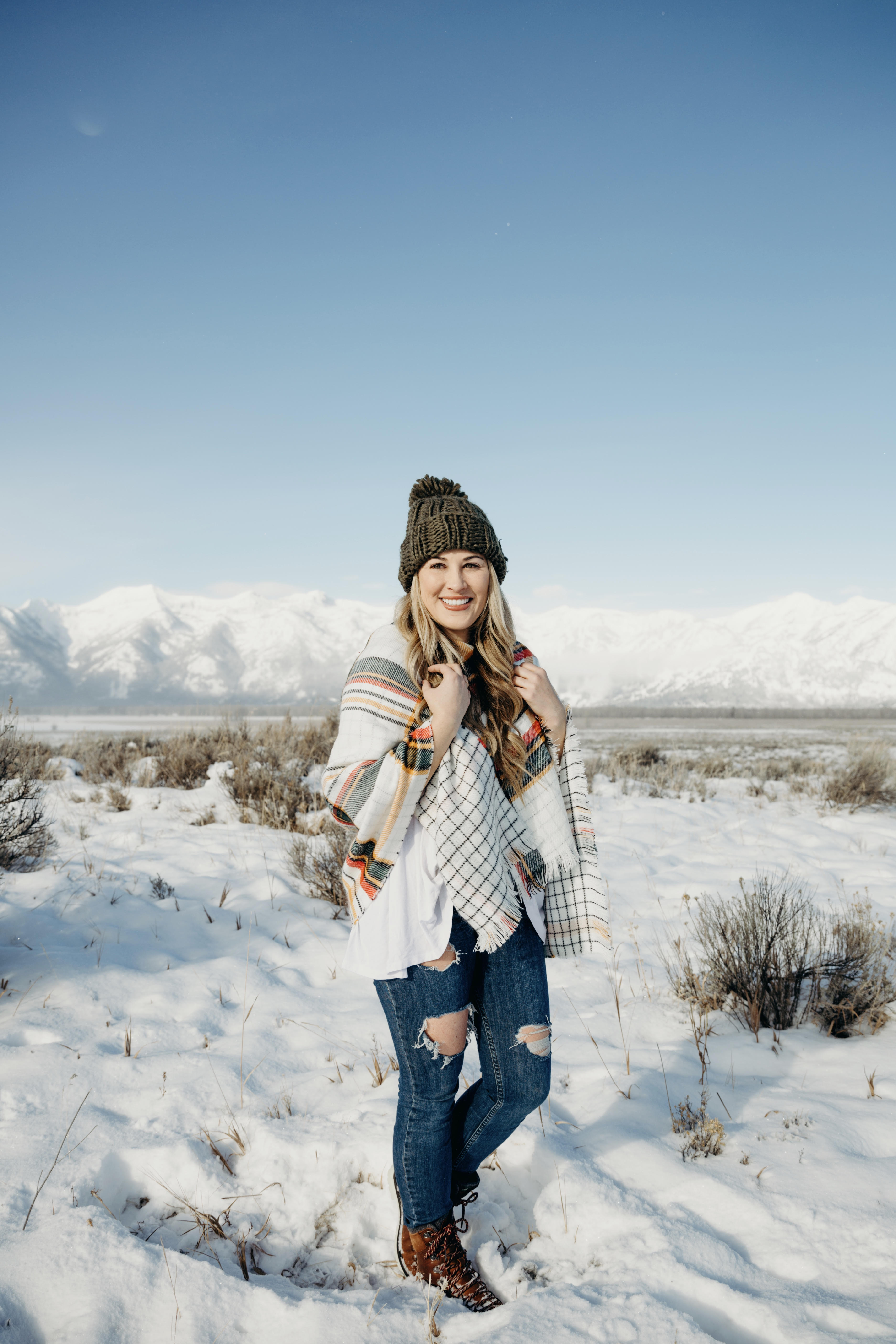 Cold Weather essentials featured by top US fashion blog, Walking in Memphis in High Heels: image of a woman wearing aGrace & Lace plaid poncho, Free People skinny jeans, Grace & Lace pom beanie, and KAMIK hiking boots