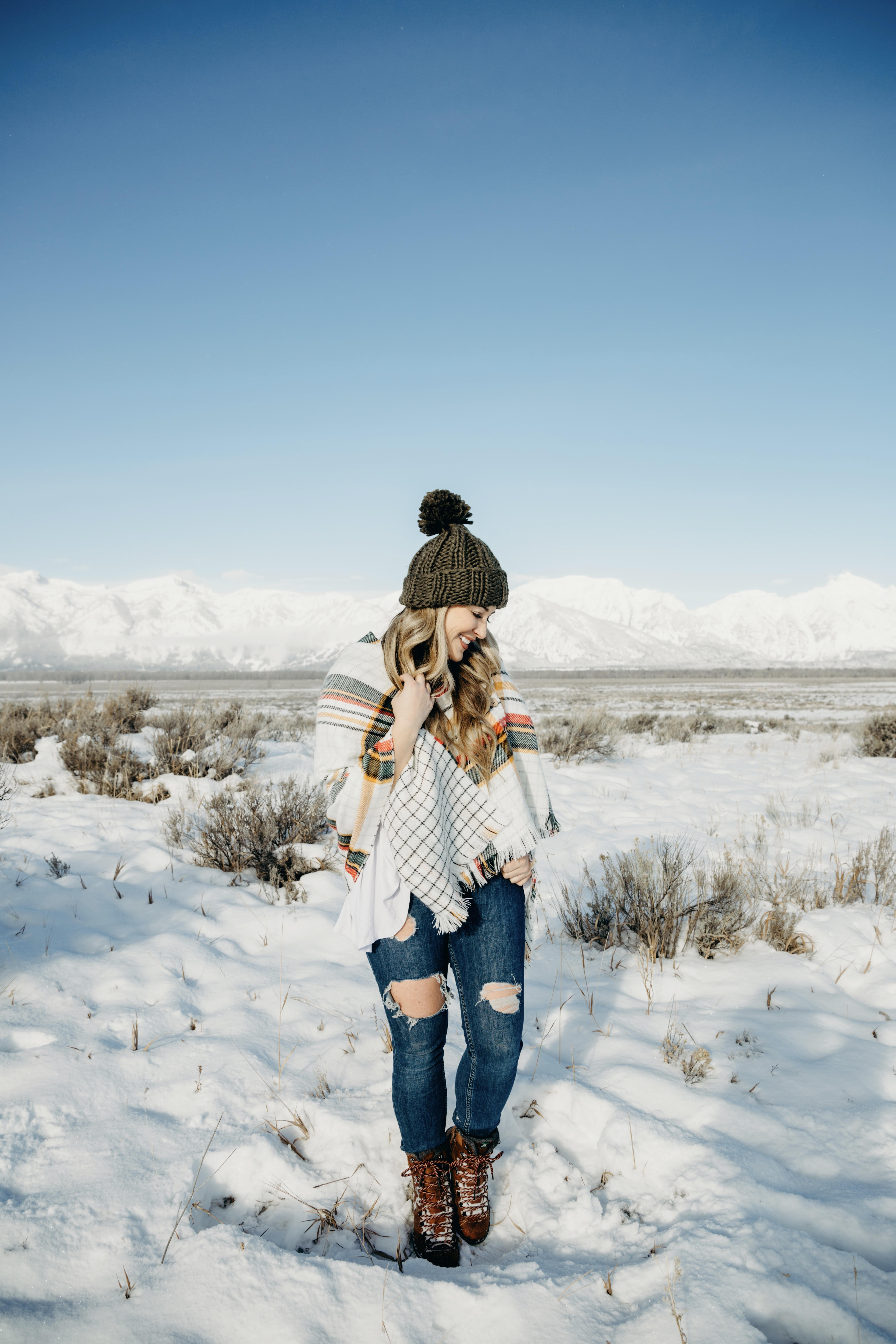Cold Weather essentials featured by top US fashion blog, Walking in Memphis in High Heels: image of a woman wearing aGrace & Lace plaid poncho, Free People skinny jeans, Grace & Lace pom beanie, and KAMIK hiking boots