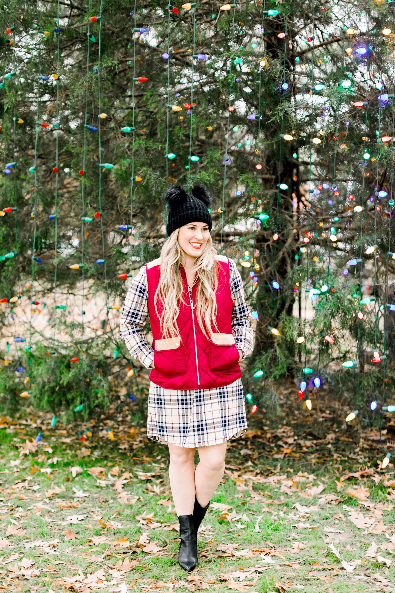 Cute Vests to layer in the Winter, featured by top US fashion blog, Walking in Memphis in High Heels: image of a woman wearing a Lauren James plaid dress, a Lauren James red vest, Sole Society black booties and an ASOS double pom pom beanie