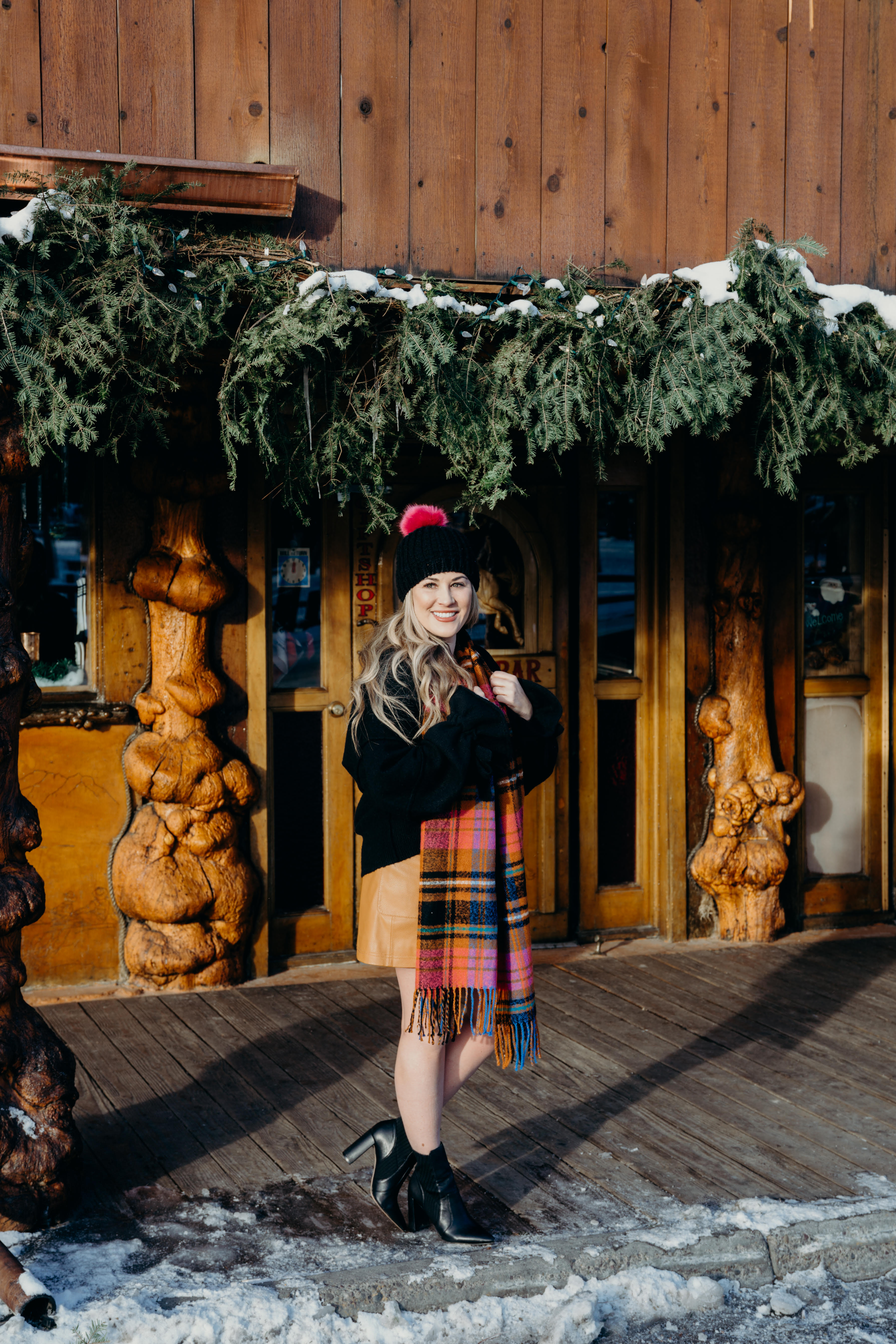 Christmas party look featured by top US fashion blog, Walking in Memphis in High Heels: image of a woman wearing a black Oracle sweater, Free People faux leather mini skirt, hot pink pom pom beanie, ASOS check scarf and Sole Society sock booties