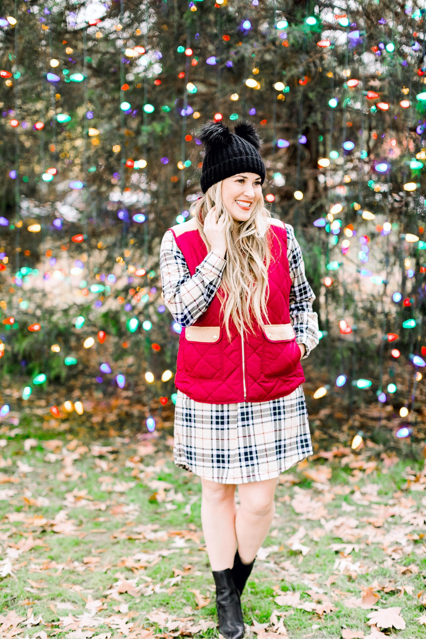 Cute Vests to layer in the Winter, featured by top US fashion blog, Walking in Memphis in High Heels: image of a woman wearing a Lauren James plaid dress, a Lauren James red vest, Sole Society black booties and an ASOS double pom pom beanie