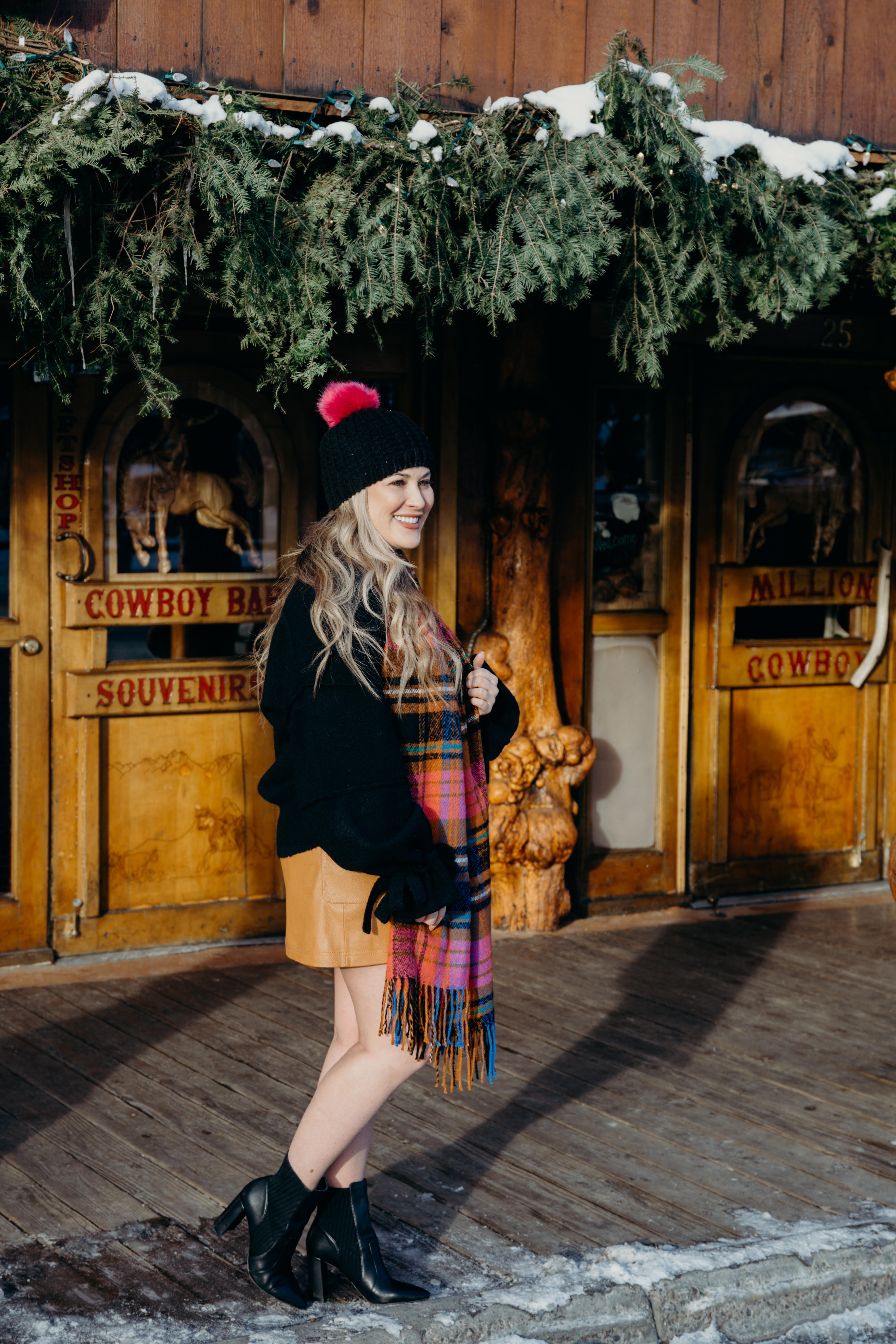 Christmas party look featured by top US fashion blog, Walking in Memphis in High Heels: image of a woman wearing a black Oracle sweater, Free People faux leather mini skirt, hot pink pom pom beanie, ASOS check scarf and Sole Society sock booties