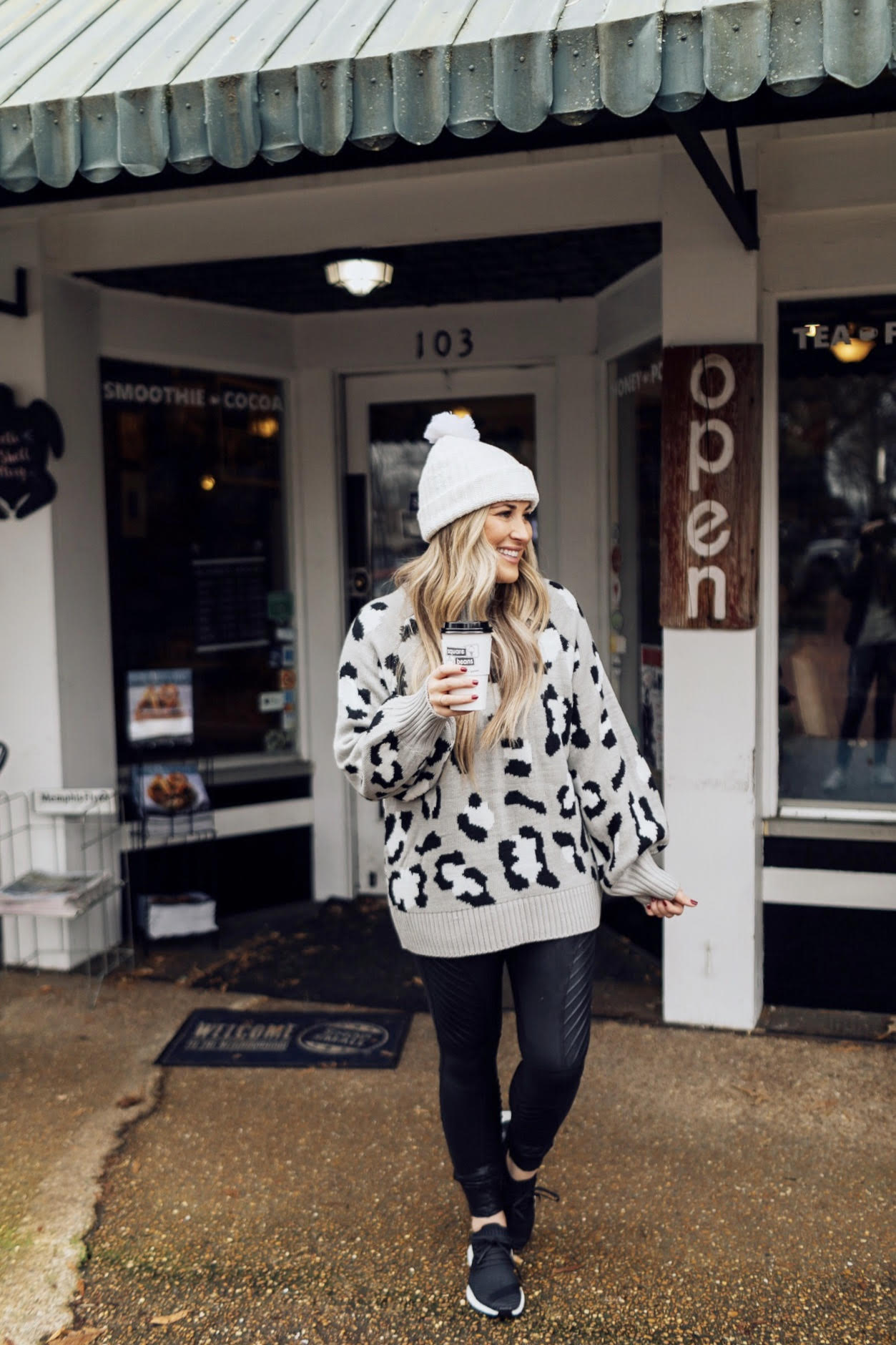 Casual winter wear styled by top US fashion blog, Walking in Memphis in High Heels: image of a woman wearing SPANX faux leather leggings, Pink Lily leopard print sweater, Adidas pink sneakers and faux fur double pom beanie hat