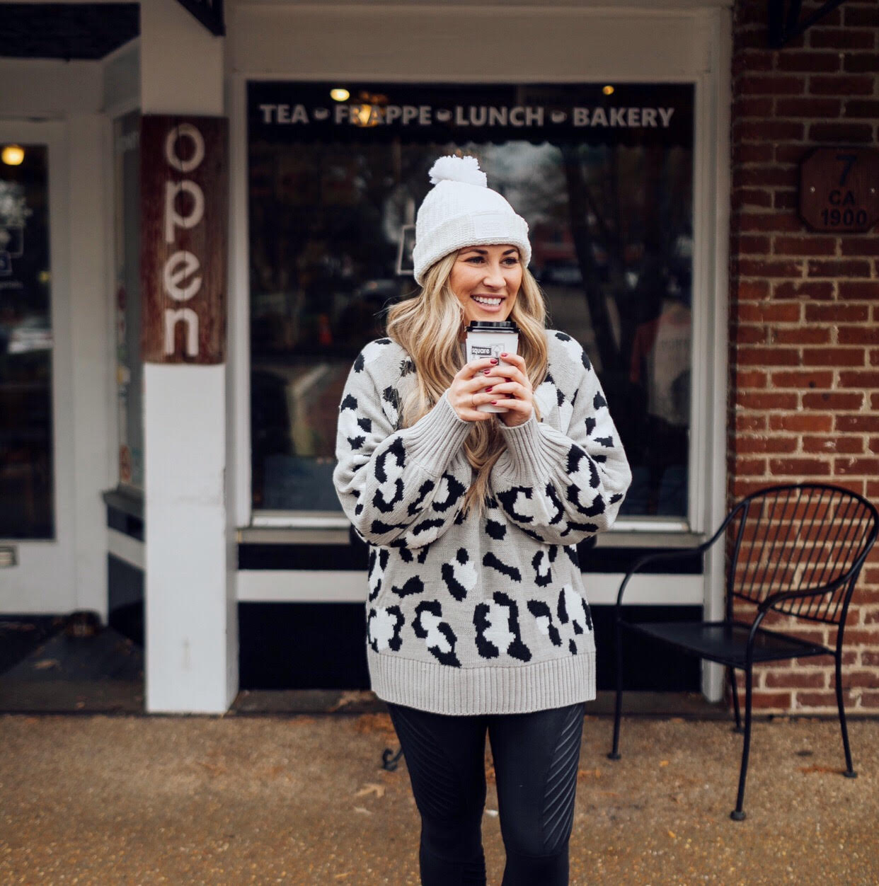 Casual winter wear styled by top US fashion blog, Walking in Memphis in High Heels: image of a woman wearing SPANX faux leather leggings, Pink Lily leopard print sweater, Adidas pink sneakers and faux fur double pom beanie hat