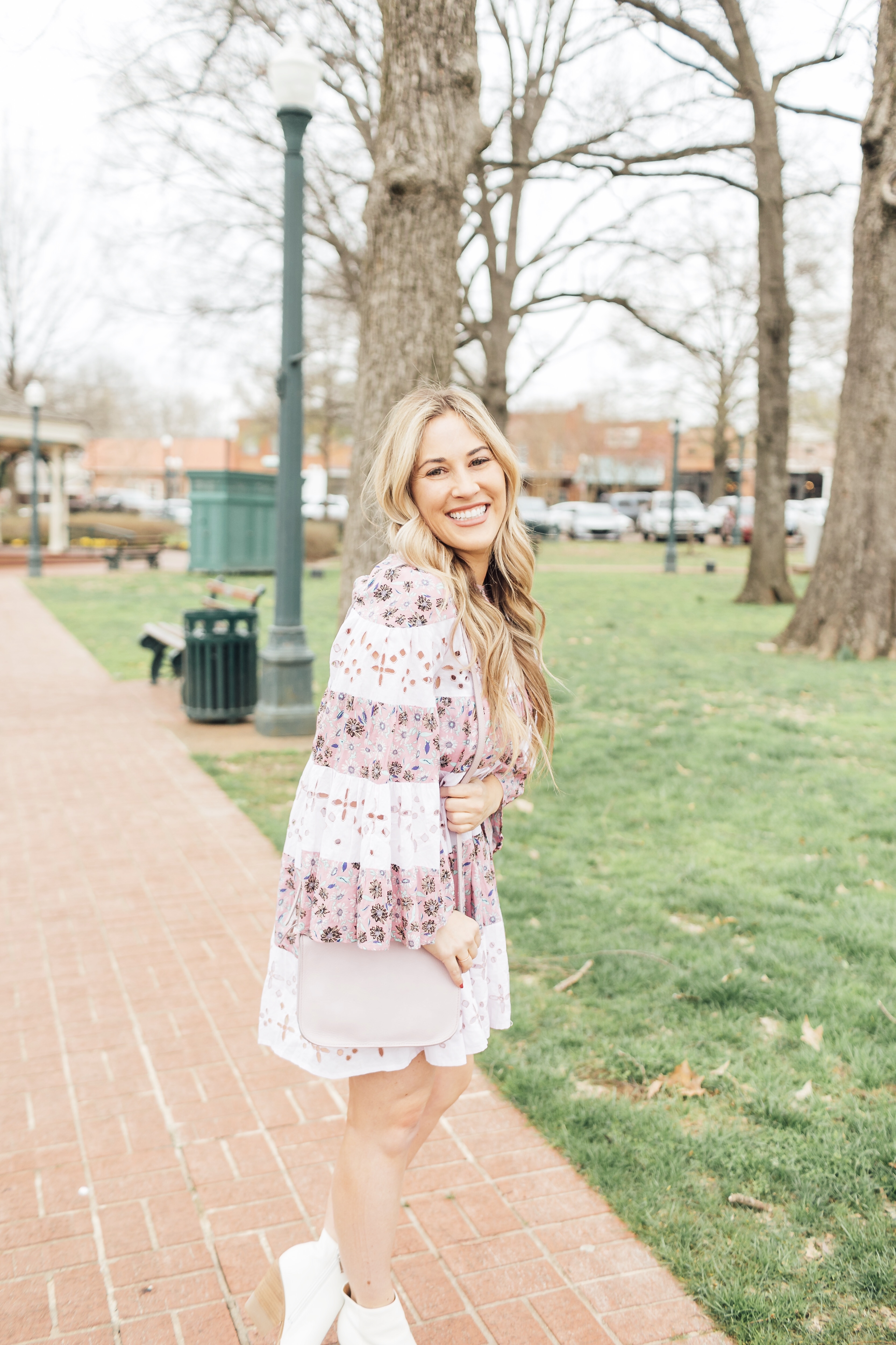 Spring style ideas featured by top US fashion blog, Walking in Memphis in High Heels: image of a woman wearing a Free People floral dress, Marc Fisher leather booties and a pink Madewell crossbody bag.