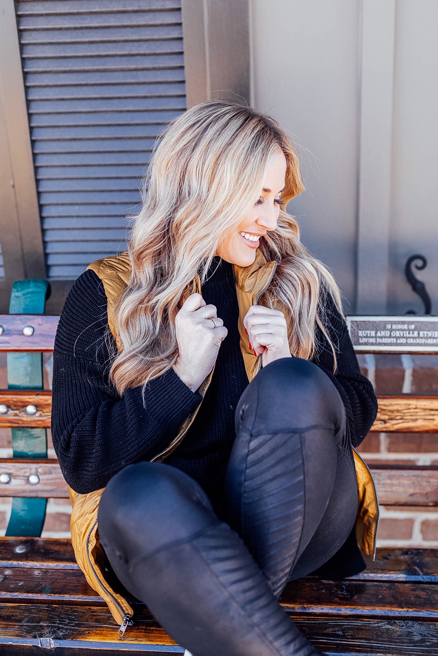 Gold Puffer Vest styled by top US fashion blog, Walking in Memphis in High Heels: image of a woman wearing a Patagonia gold puffer vest, SPANX faux leather leggings, Target tunic sweater, Adidas sneakers, and a LA Dodgers camouflage baseball cap.