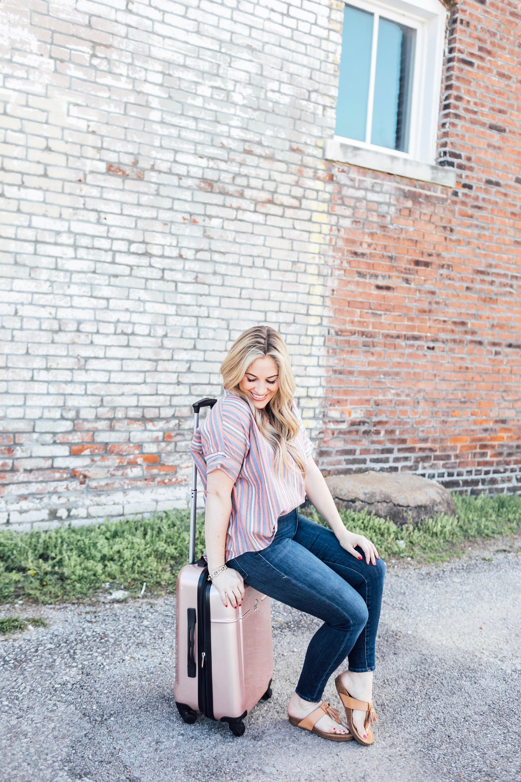 Spring Trip Packing List featured by top US travel and fashion blog, Walking in Memphis in High Heels: image of a woman with a Delsey spinner carry one suitcase