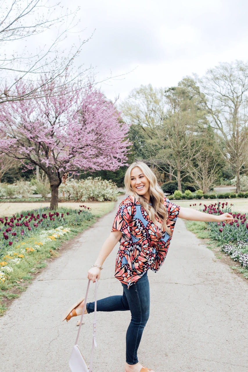 How to Add Color to Your Wardrobe for Spring featured by top US fashion blog, Walking in Memphis in High Heels: image of a woman wearing a Sugar Boutique patterned colorful top, Good American skinny jeans, Madewell crossbody bag, and Steve Madden sandals.