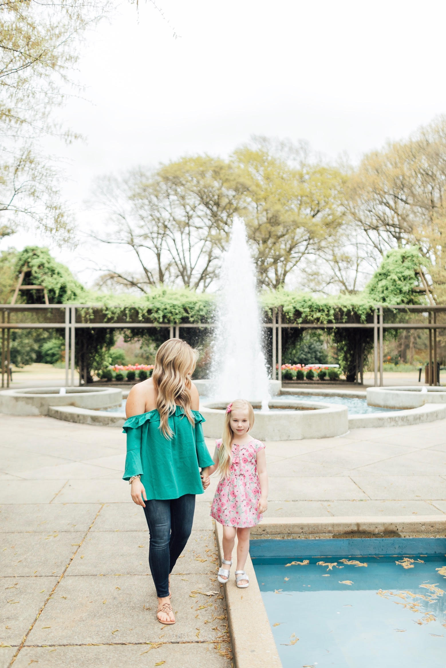 How to Get Cute Family Pictures with Your Child featured by top US life and style blog, Walking in Memphis in High Heels: image of a woman wearing a BB Dakota off the shoulder blouse, Good American skinny jeans, Tory Burch flies flops and her daughter wearing an Egg Baby floral dress and Pediped silver sandals