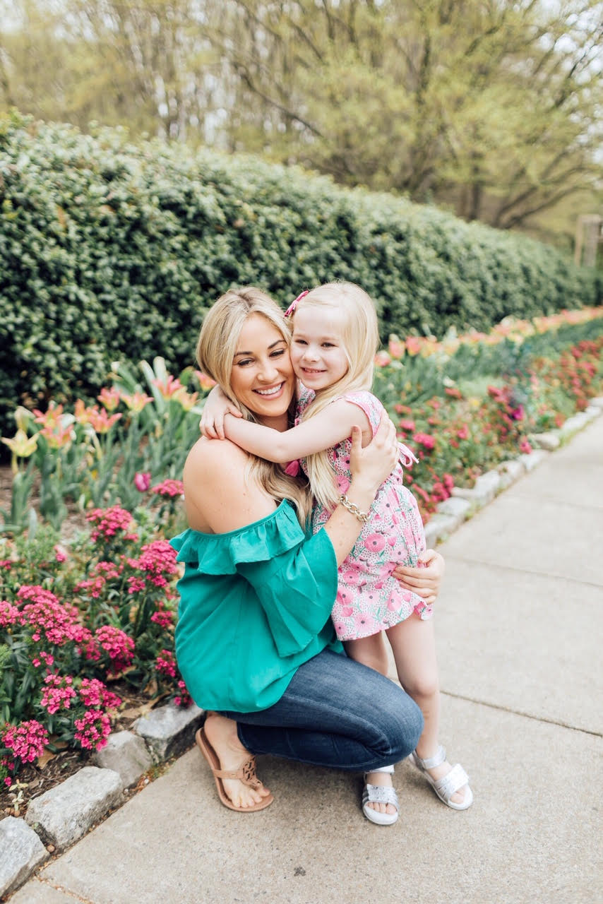 How to Get Cute Family Pictures with Your Child featured by top US life and style blog, Walking in Memphis in High Heels: image of a woman wearing a BB Dakota off the shoulder blouse, Good American skinny jeans, Tory Burch flies flops and her daughter wearing an Egg Baby floral dress and Pediped silver sandals