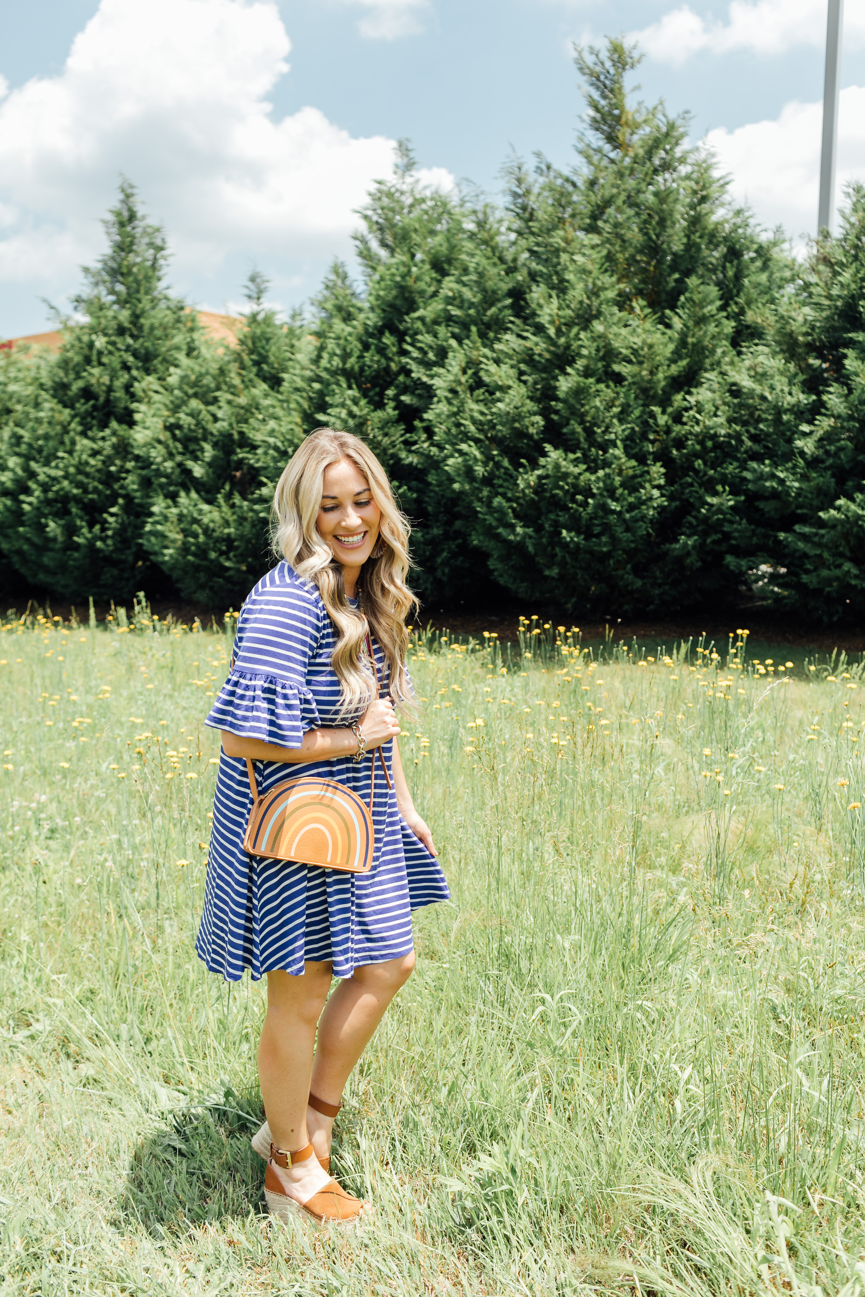 Cute summer dress styled by top US fashion blog, Walking in Memphis in High Heels: image of a woman wearing a Pink Blush striped dress, Marc Fisher platform espadrille wedge sandals, Chico’s colorful bead necklace, and a Madewell rainbow stripe pouch