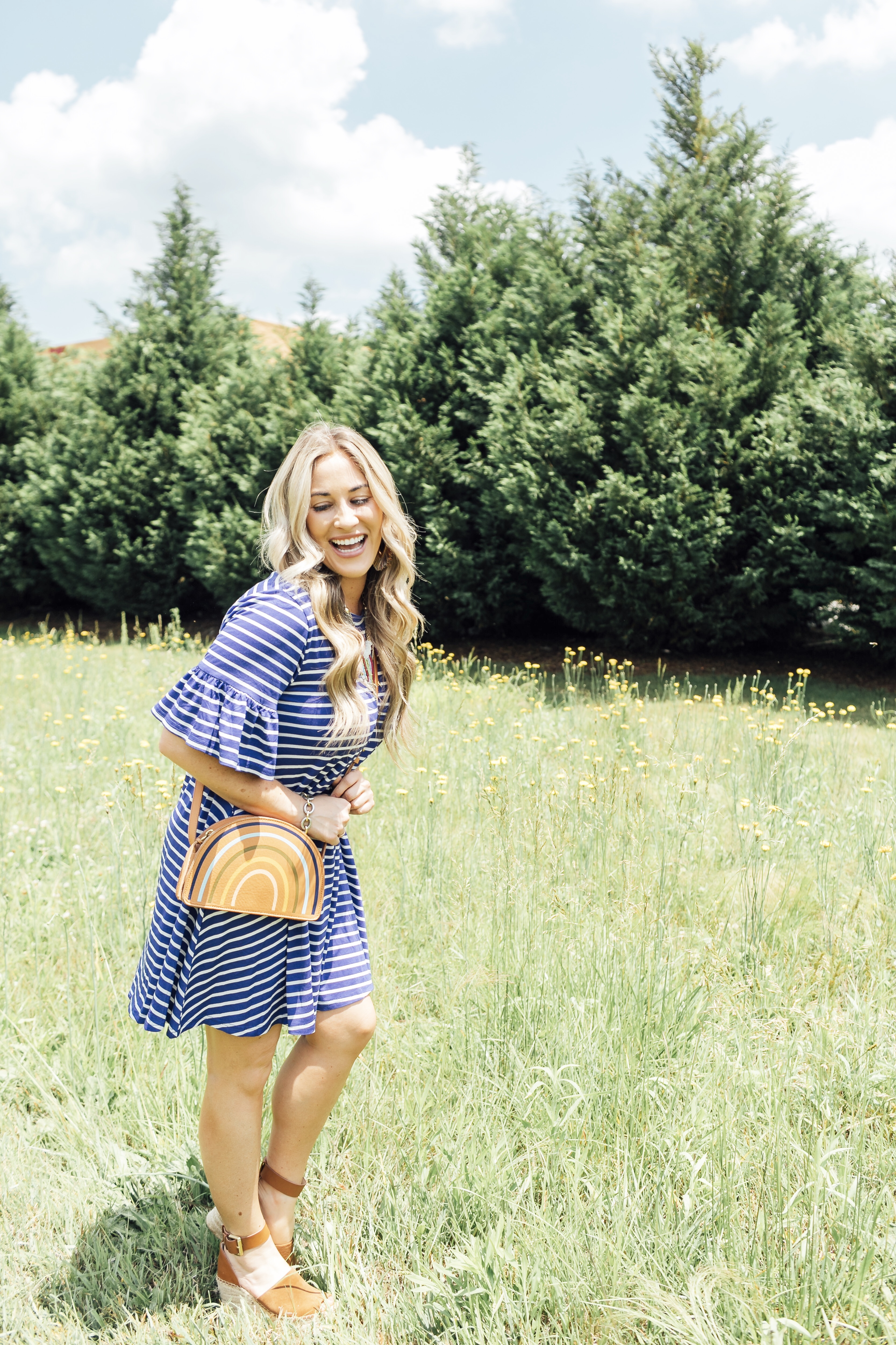 Cute summer dress styled by top US fashion blog, Walking in Memphis in High Heels: image of a woman wearing a Pink Blush striped dress, Marc Fisher platform espadrille wedge sandals, Chico’s colorful bead necklace, and a Madewell rainbow stripe pouch