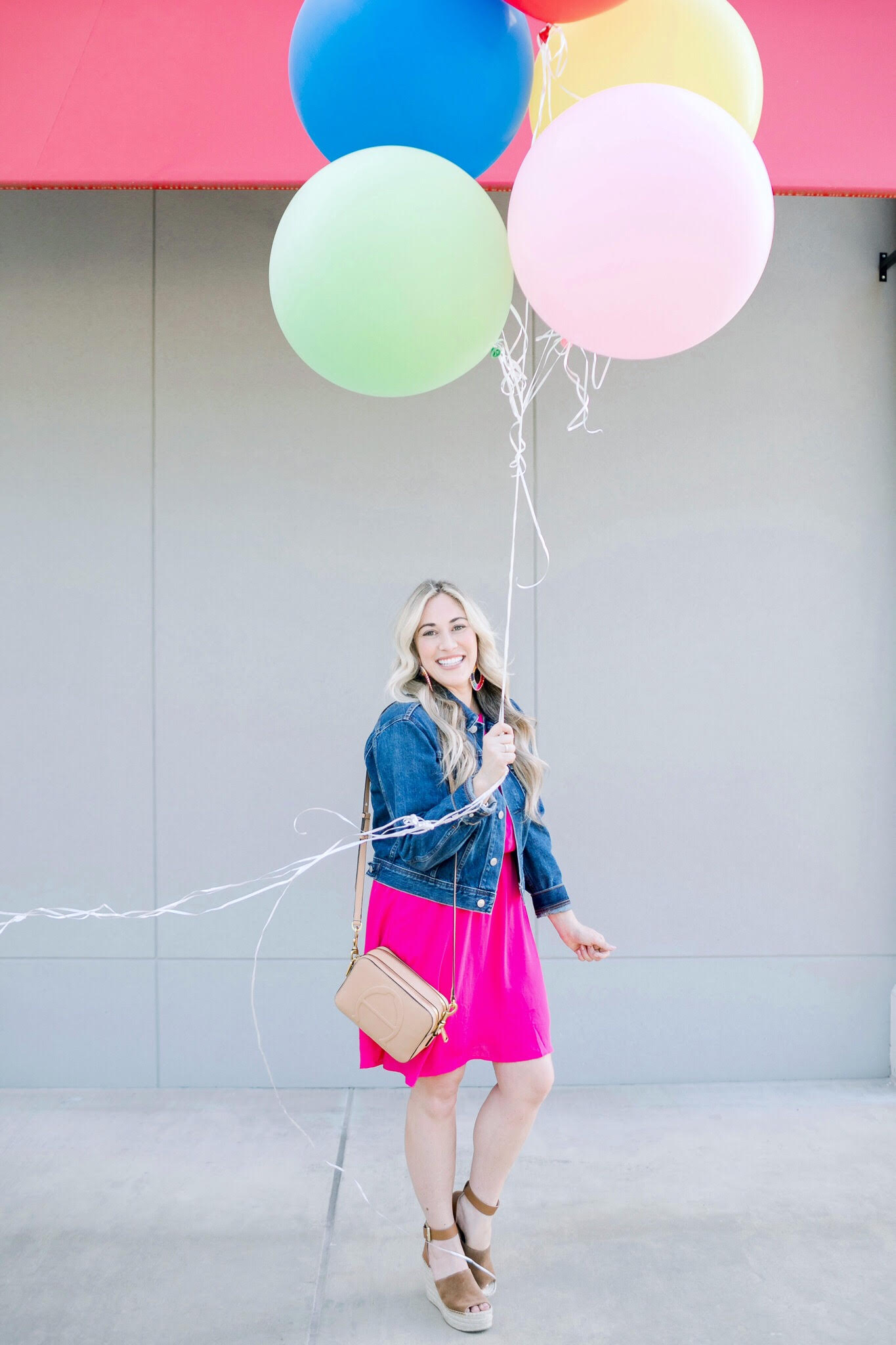 Cute summer dresses featured by top US fashion blog, Walking in Memphis in High Heels: image of a woman wearing a Gordmans pink halter neck dress, Everlane cropped denim jacket, Marc Fisher wedge sandals, and Baublebar raffia statement earrings.