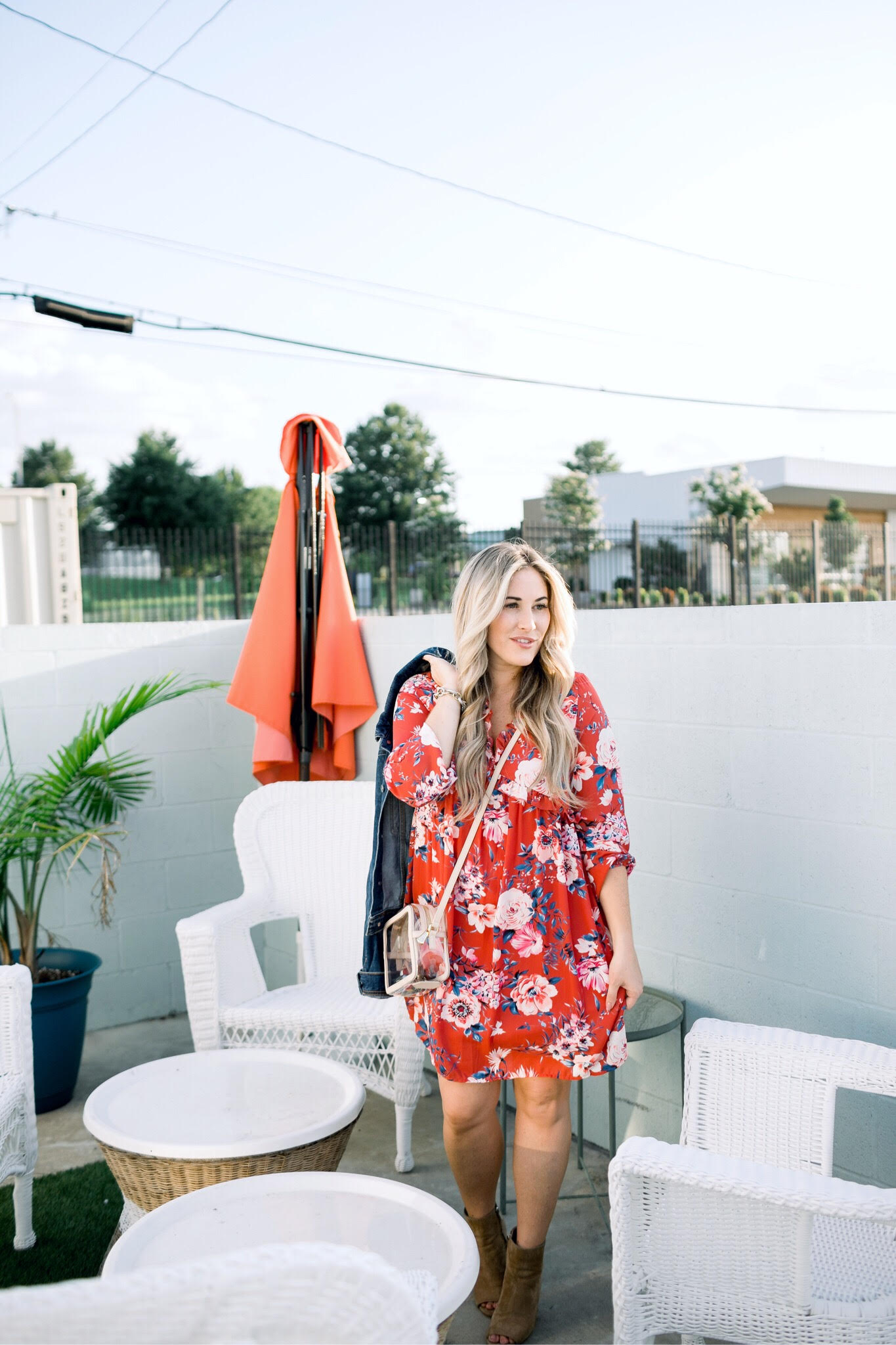 Cute summer dresses to transition into fall featured by top US fashion blog: image of a woman wearing a Pink Lily Boutique red floral dress, Everyone denim jacket, Sam Edelman shorties, and GiGi New York crossbody bag.