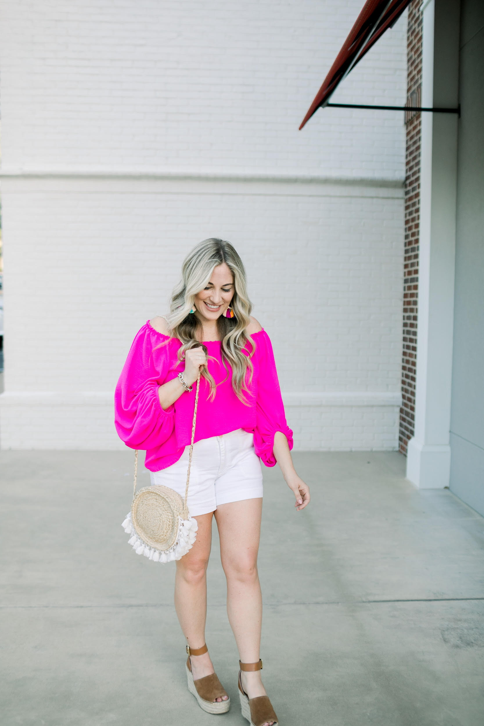 Top 10 Colorful Summer Pieces to Add to Your Closet featured by top US fashion blog, Walking in Memphis in High Heels: image of a woman wearing a pink Hazel & Olive off the shoulder pink top, Baublebar raffia statement earrings, Marc Fisher wedge sandals, and Anthropologie palazzo shorts.