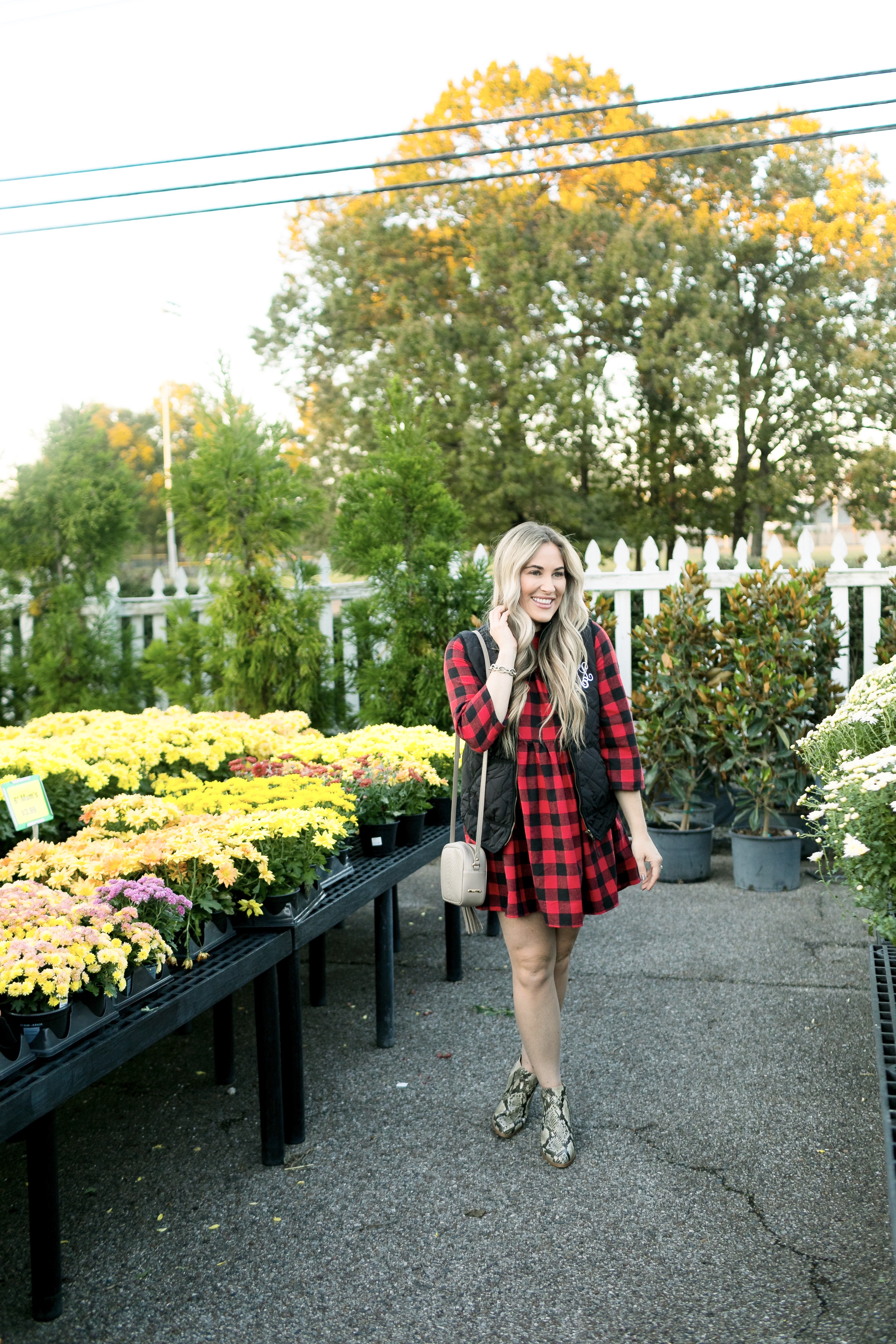 How to layer clothes in the fall, tips featured by top US fashion blog, Walking in Memphis in High Heels: image of a woman wearing a SheIn plaid smock dress, MarleyLilly monogrammed puffer vest, and Vince Camuto snakeskin booties.