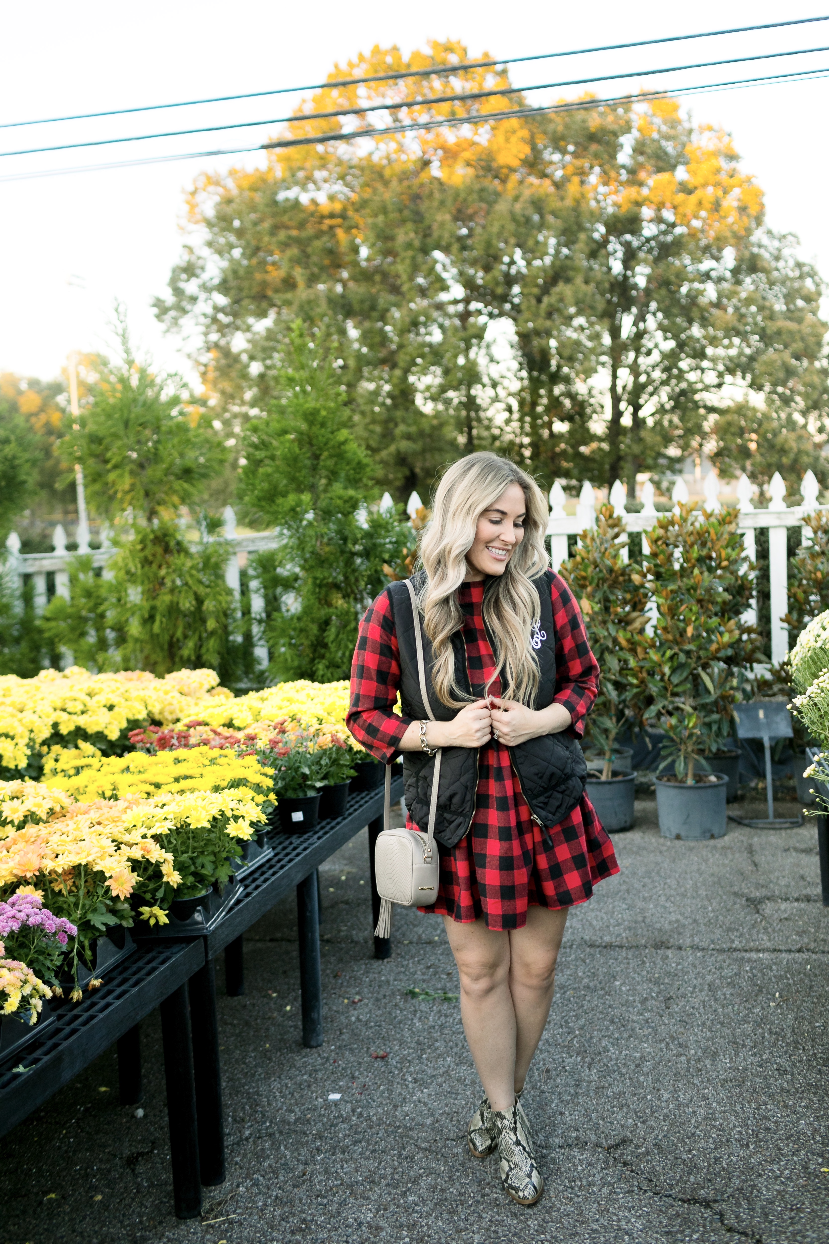 How to layer clothes in the fall, tips featured by top US fashion blog, Walking in Memphis in High Heels: image of a woman wearing a SheIn plaid smock dress, MarleyLilly monogrammed puffer vest, and Vince Camuto snakeskin booties.