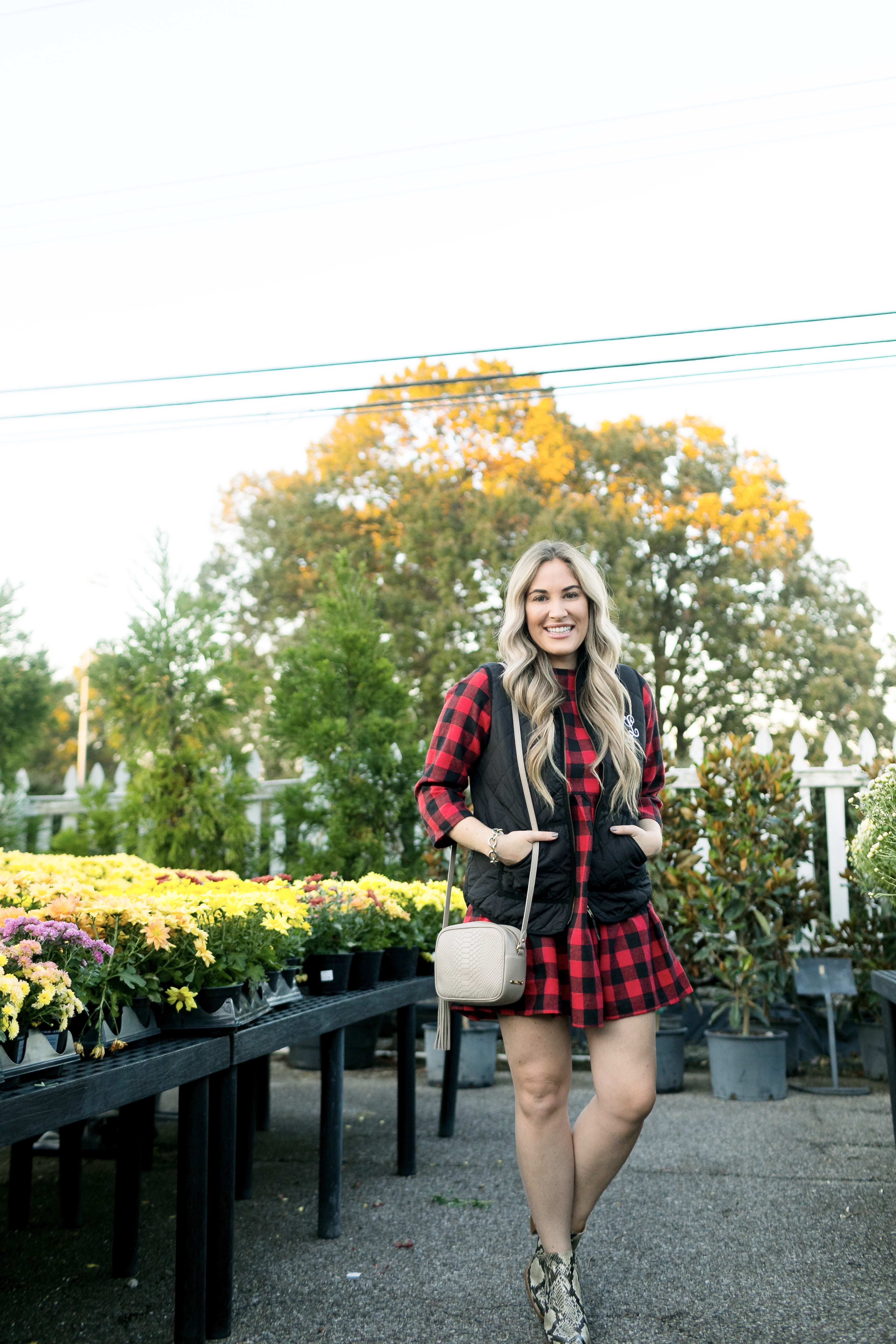 How to layer clothes in the fall, tips featured by top US fashion blog, Walking in Memphis in High Heels: image of a woman wearing a SheIn plaid smock dress, MarleyLilly monogrammed puffer vest, and Vince Camuto snakeskin booties.