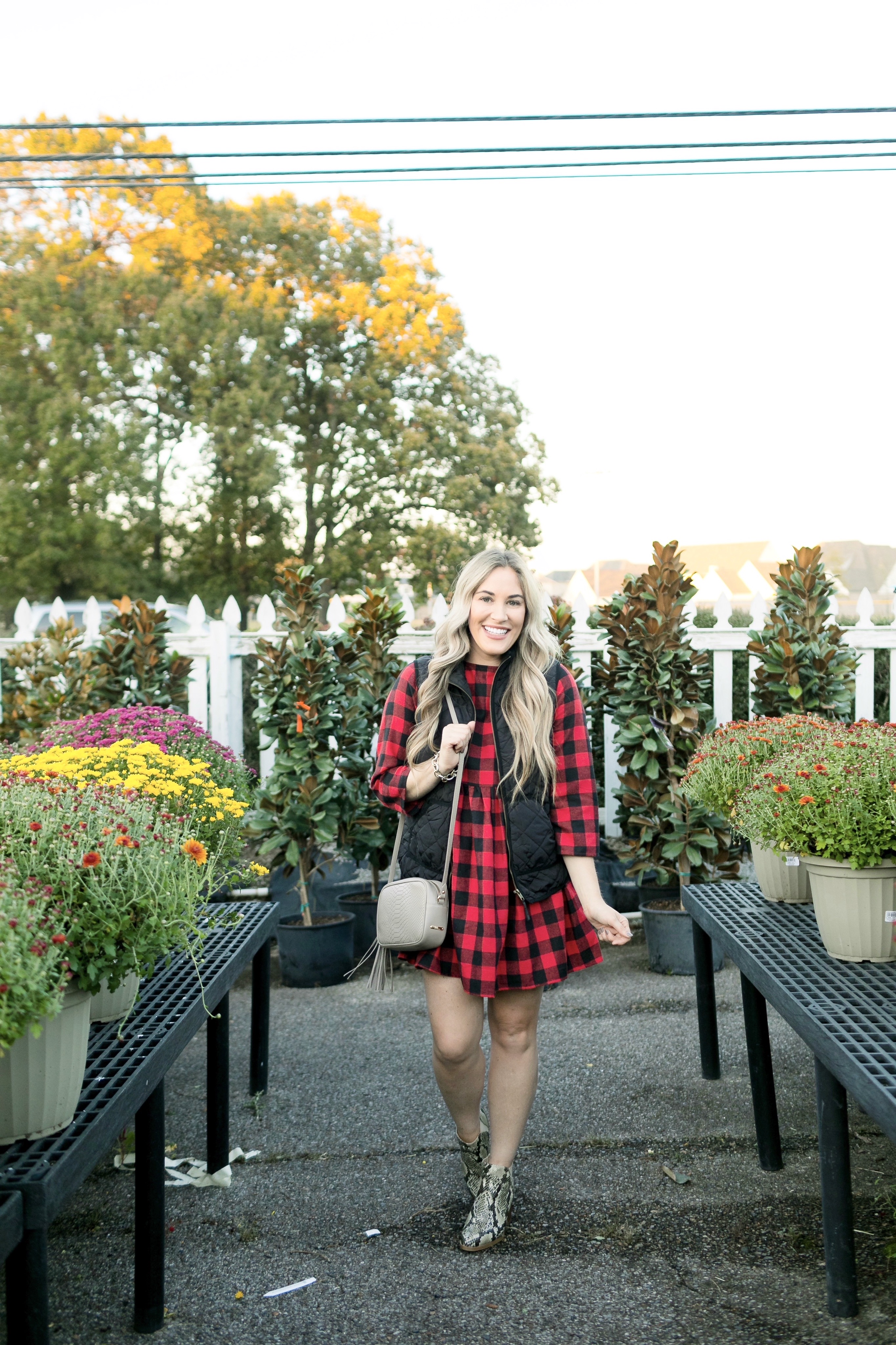 How to layer clothes in the fall, tips featured by top US fashion blog, Walking in Memphis in High Heels: image of a woman wearing a SheIn plaid smock dress, MarleyLilly monogrammed puffer vest, and Vince Camuto snakeskin booties.