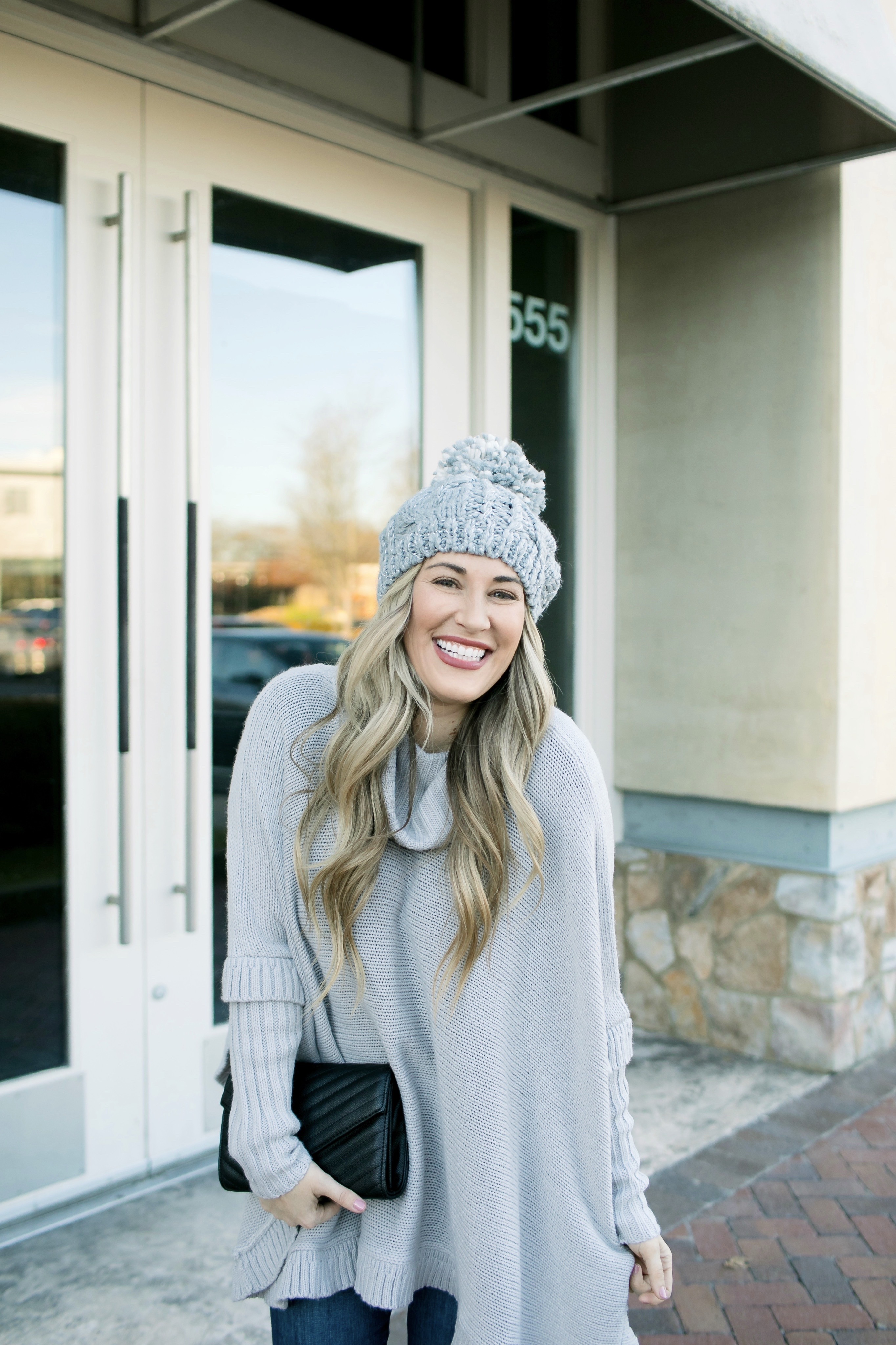 Last Minute Stocking Stuffers from Francesca's at Carriage Crossing featured by top US fashion blog, Walking in Memphis in High Heels: image of a woman wearing Francesca's straight jeans, a quilted clutch, a beanie hat and and a poncho.