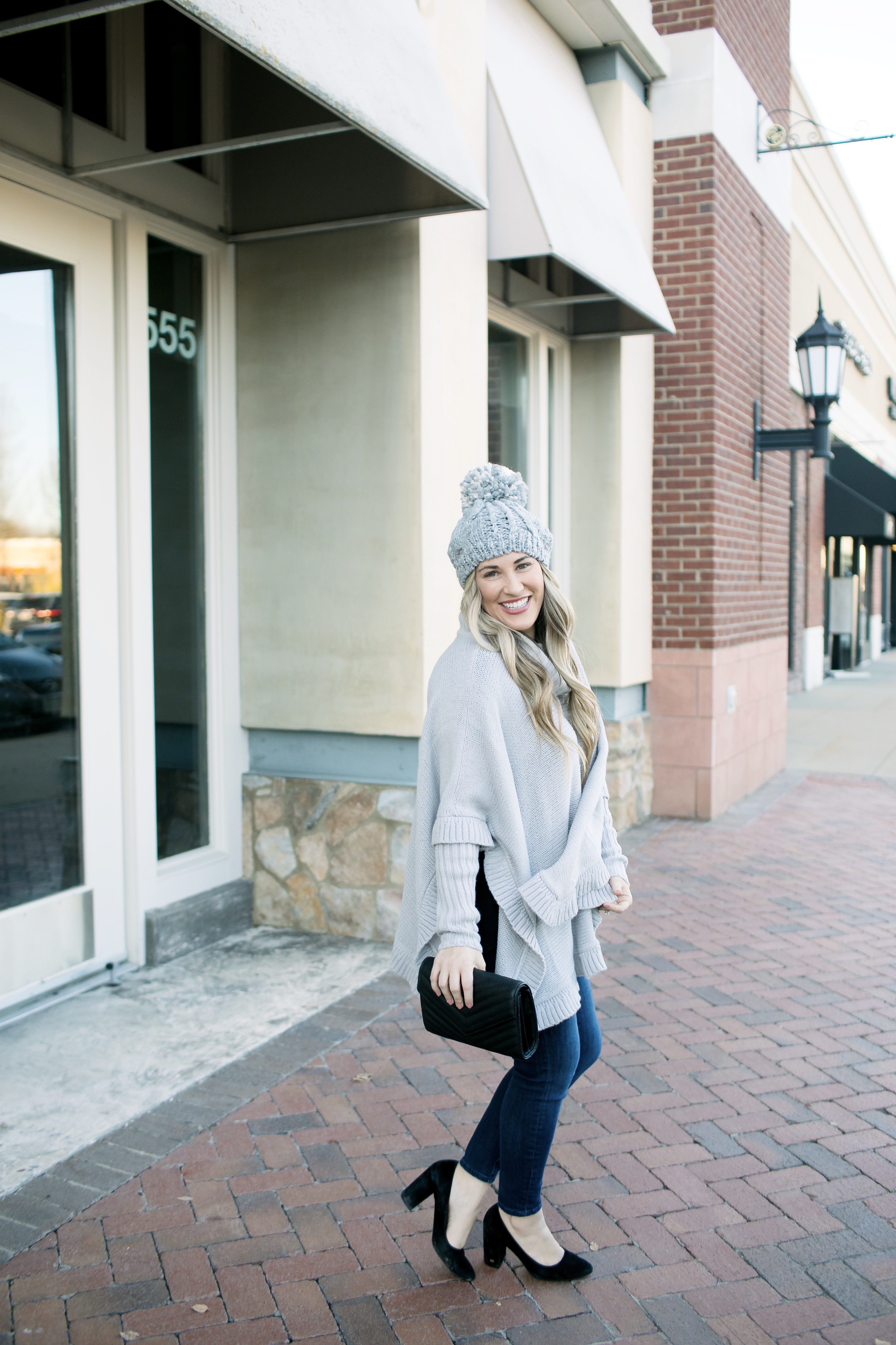 Last Minute Stocking Stuffers from Francesca's at Carriage Crossing featured by top US fashion blog, Walking in Memphis in High Heels: image of a woman wearing Francesca's straight jeans, a quilted clutch, a beanie hat and and a poncho.