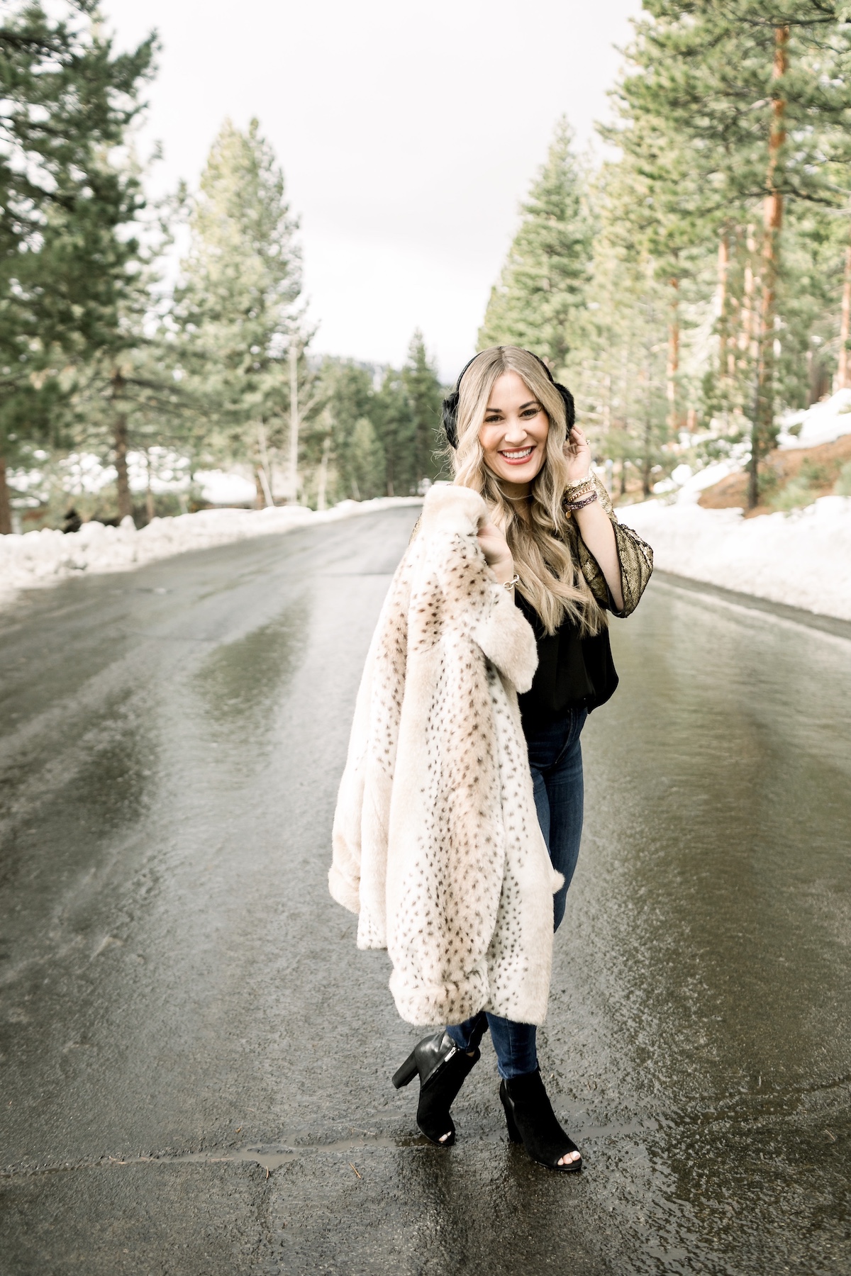 Winter Essentials featured by top Memphis fashion blog, Walking in Memphis in High Heels: image of a woman wearing an ARIAT top, Dennis Basso leopard faux fur coat, Good American high rise skinny jeans, Enzo Angiolini booties, and Surell earmuffs.