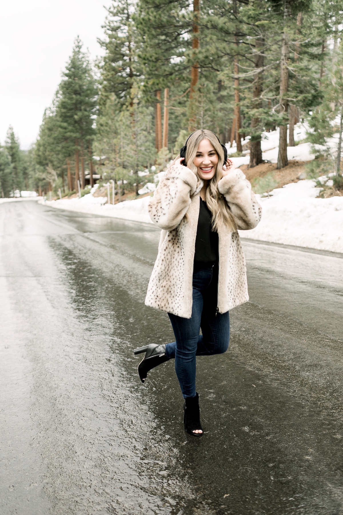 Winter Essentials featured by top Memphis fashion blog, Walking in Memphis in High Heels: image of a woman wearing an ARIAT top, Dennis Basso leopard faux fur coat, Good American high rise skinny jeans, Enzo Angiolini booties, and Surell earmuffs.