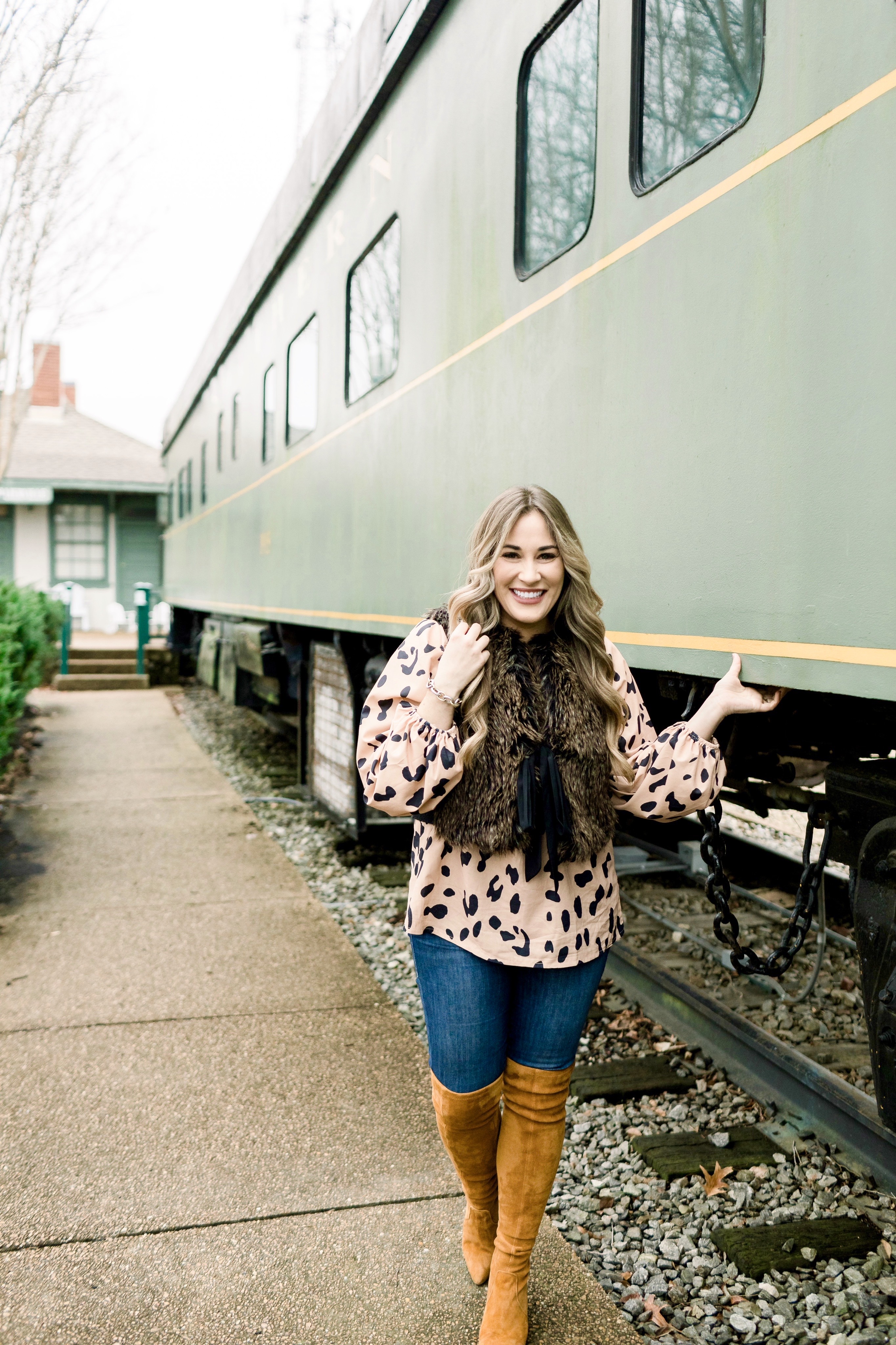 Animal print top styled by top Memphis fashion blog, Walking in Memphis in High Heels: image of a woman wearing an Amazon Chiffon animal print top, LOFT faux fur vest, Good American jeans and Goodnight Macaroon over the knees suede boots.
