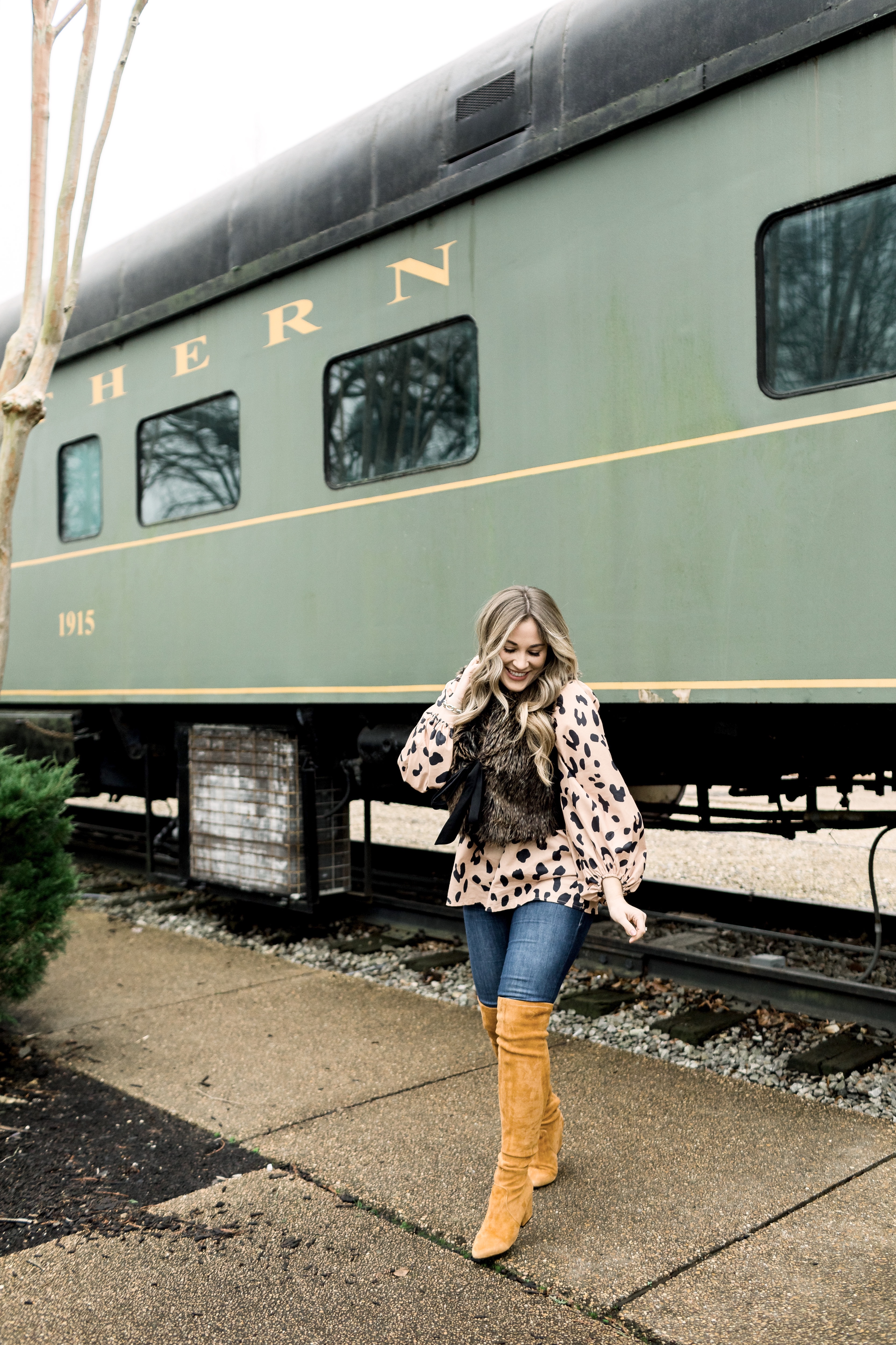 Animal print top styled by top Memphis fashion blog, Walking in Memphis in High Heels: image of a woman wearing an Amazon Chiffon animal print top, LOFT faux fur vest, Good American jeans and Goodnight Macaroon over the knees suede boots.
