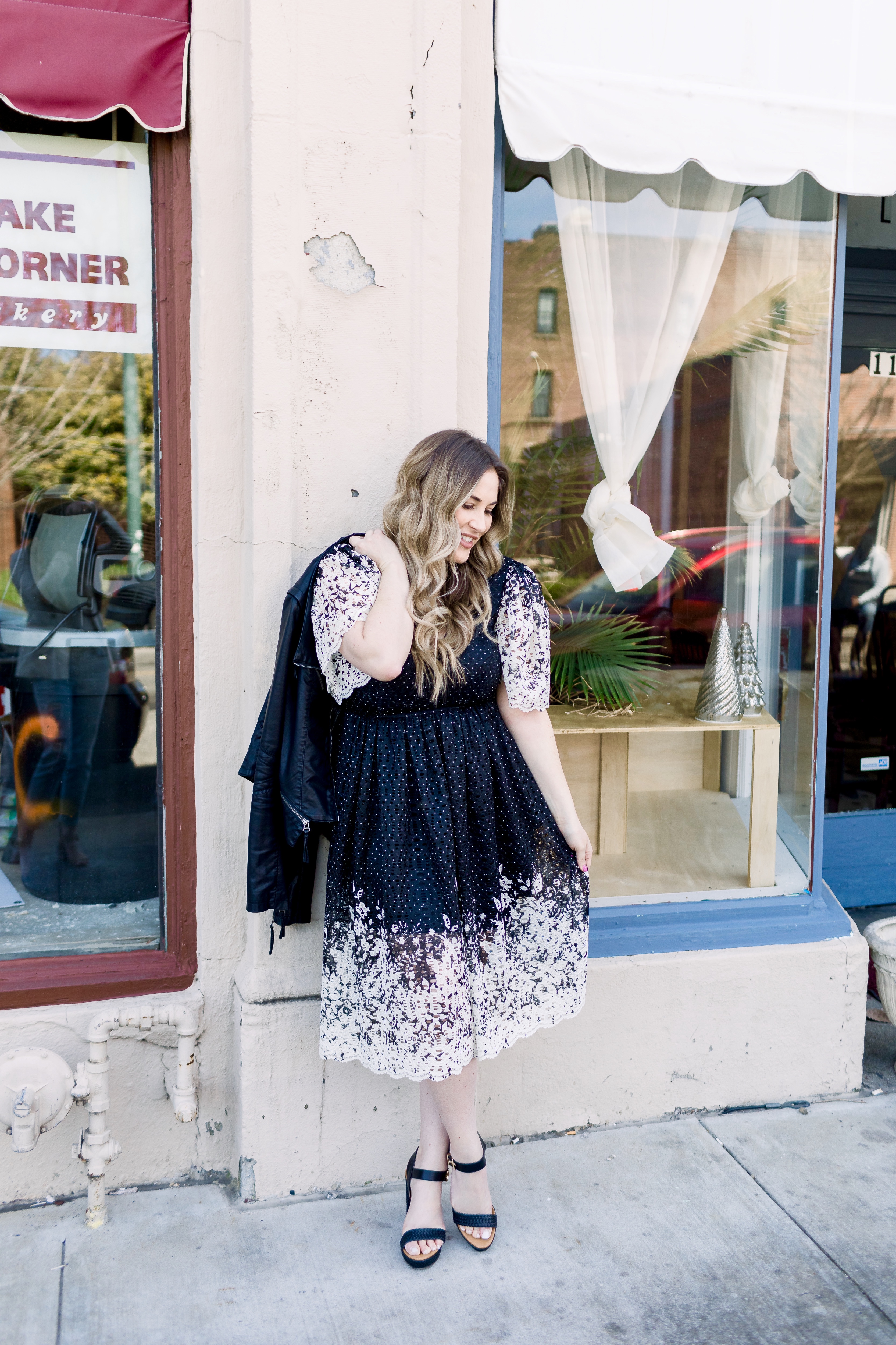 How to wear black in the spring, styling tips featured by top Memphis fashion blog, Walking in Memphis in High Heels: image of a woman wearing a black and white Eliza J lace dress, Levi’s faux leather Moto jacket, RAID platform sandals.