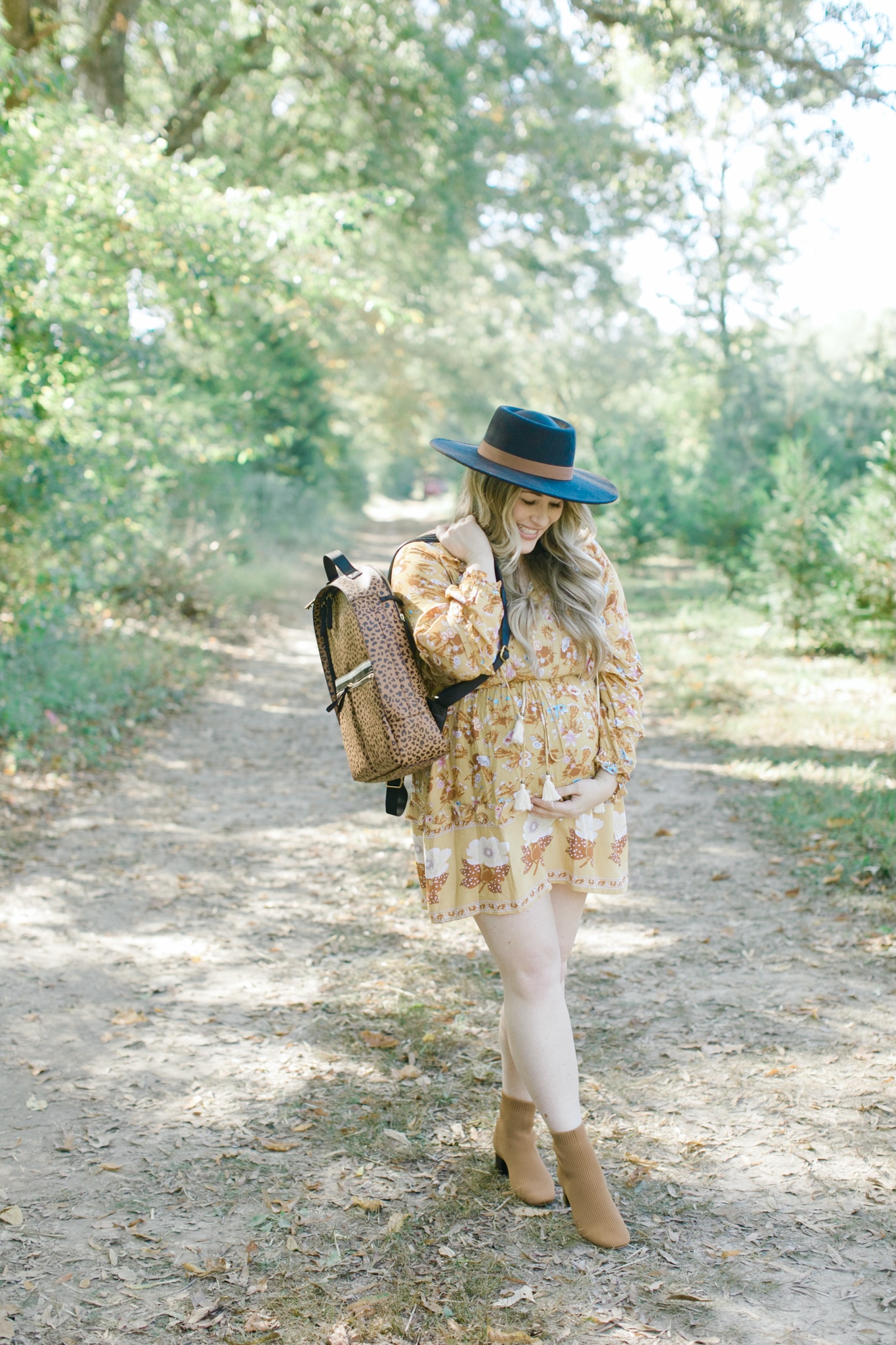 Fall style featured by top Memphis fashion blogger, Walking in Memphis in High Heels: image of a woman wearing a Red Dress floral yellow dress, Everyone booties, and a Fossil backpack.