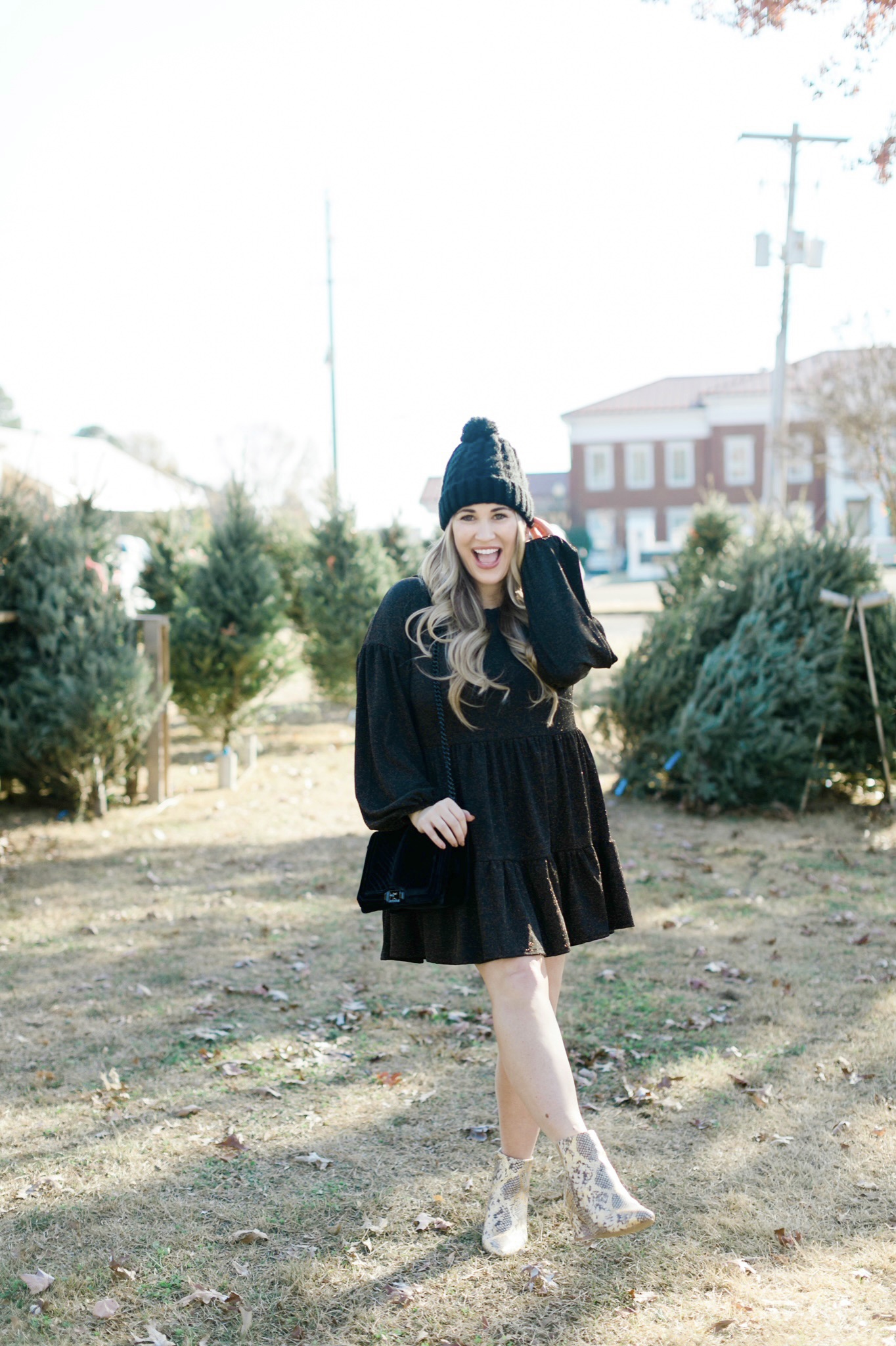 New Years Eve Outfits featured by top Memphis fashion blogger, Walking in Memphis in High Heels: Image of a woman wearing an RBBK holiday dress, Express faux fur coat, Tasha pom beanie, and Red Dress ankle booties