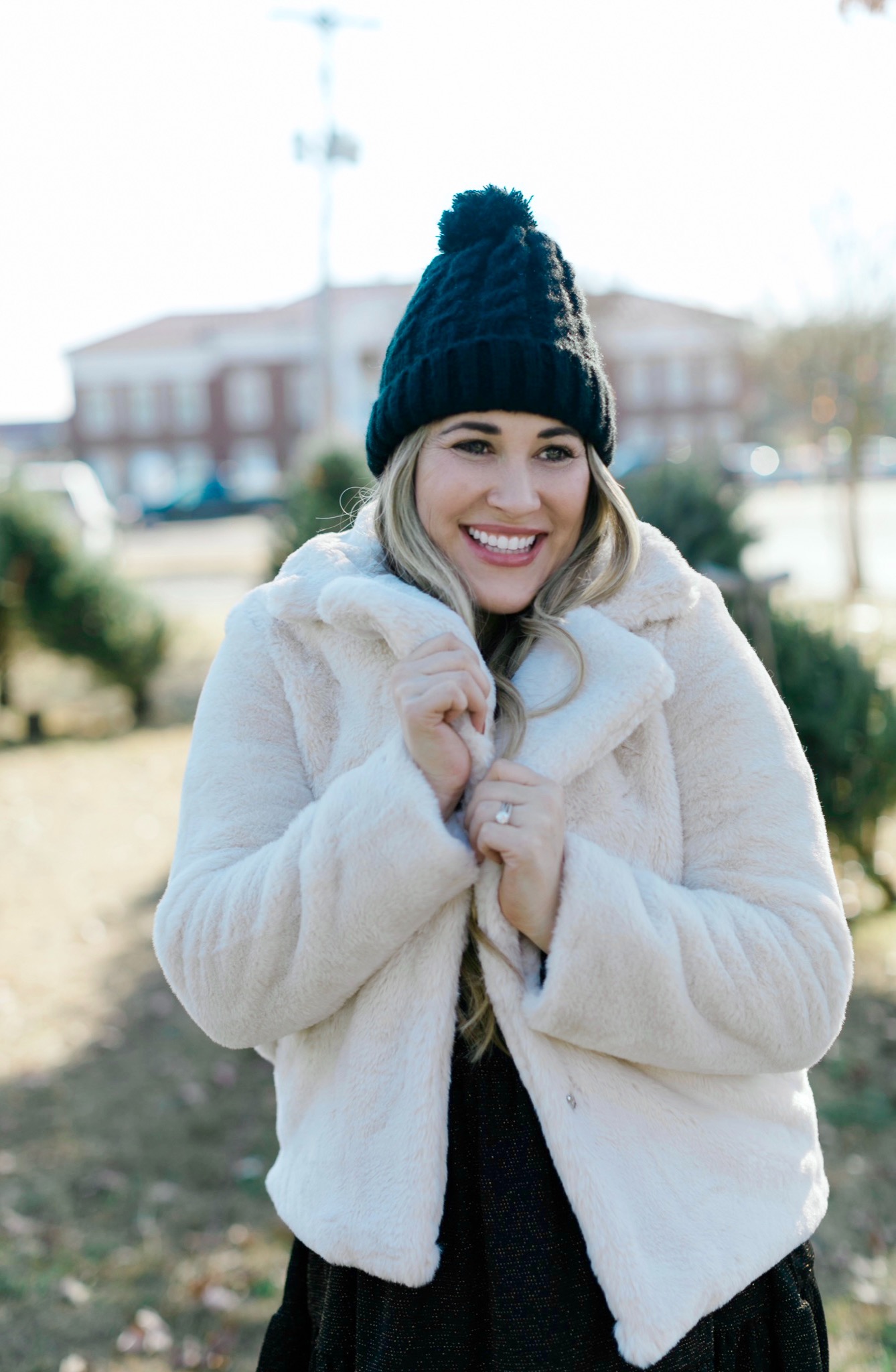 New Years Eve Outfits featured by top Memphis fashion blogger, Walking in Memphis in High Heels: Image of a woman wearing an RBBK holiday dress, Express faux fur coat, Tasha pom beanie, and Red Dress ankle booties