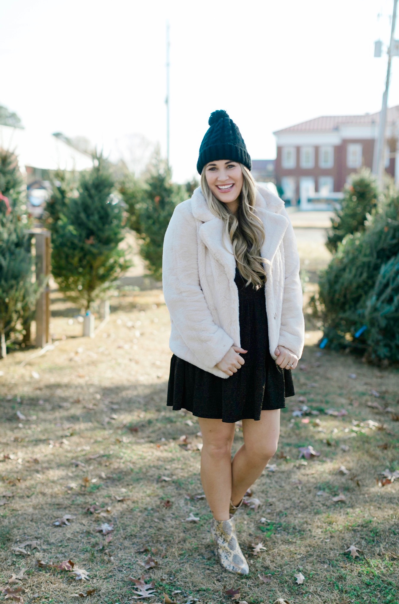 New Years Eve Outfits featured by top Memphis fashion blogger, Walking in Memphis in High Heels: Image of a woman wearing an RBBK holiday dress, Express faux fur coat, Tasha pom beanie, and Red Dress ankle booties